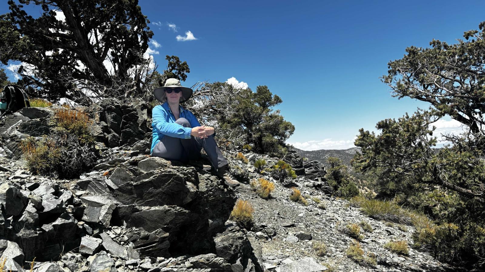 Nikki Moore sits on a pile of large rocks in the Sierra Nevada